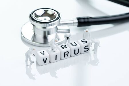 Spreading or coronavirus, COV, COVID-19 flu outbreak concept, miniature people doctors with protective suit inspecting cube block combine the word Virus with stethoscope.の写真素材