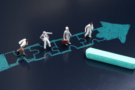 Business success with teamwork, job and career path or partnership concept, miniature people businessmen standing in drawing jigsaw with arrow in same direction with chalk on blackboard.の写真素材