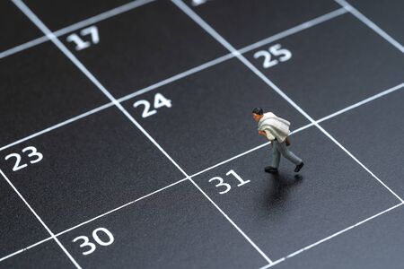 Business schedule plan, travel date or end of month pay day for salary man concept, miniature people businessman figure with suitcase walking on 31 end of month calendar.の写真素材