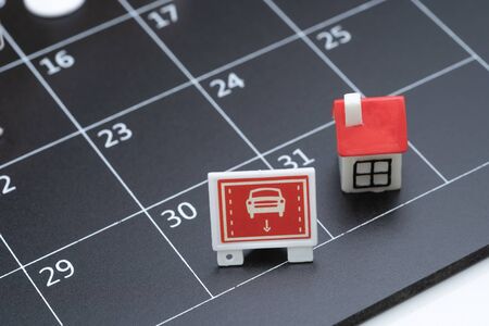 Car installment payment, pay for car and house rent deadline reminder or new car planning schedule concept, miniature car sign and house at the end of month on black calendar.の写真素材