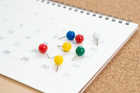 Colorful thumbtack, pushpin or pins on calendar concept for busy meeting schedule, reminder or special event and important appointment date.の写真素材
