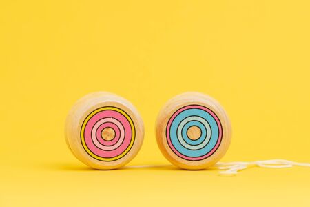 Wooden yoyo or yo-yo toy on solid yellow background with copy space using as volatility and risk in...