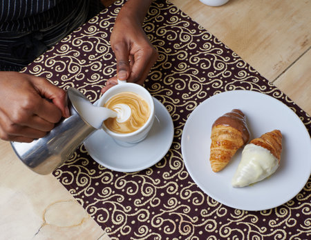 Breakfast croissants and hands making a coffee with milk in a table backgroundの写真素材