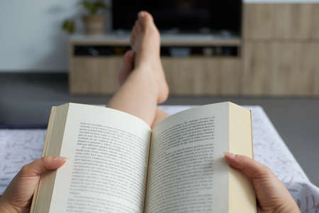 A woman reading a book relaxed on the sofaの写真素材
