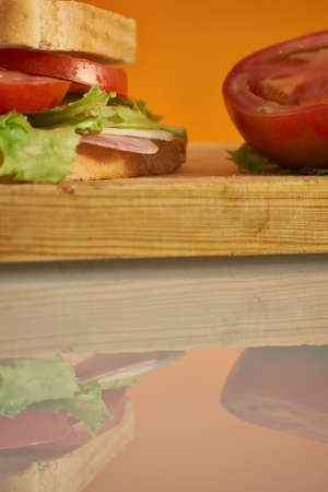 Healthy ham and cheese sandwich with tomato and lettuce in orange backgroundの写真素材