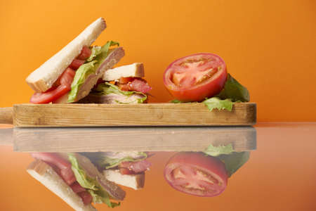 Healthy ham and cheese sandwich with tomato and lettuce in orange backgroundの写真素材