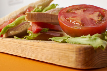 Healthy ham and cheese sandwich with tomato and lettuce in orange backgroundの写真素材