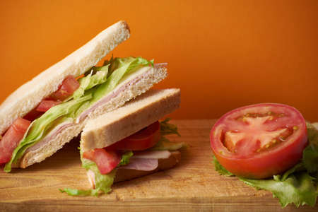Healthy ham and cheese sandwich with tomato and lettuce in orange backgroundの写真素材