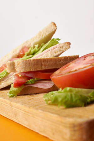 A ham and cheese sandwich with tomato an lettuce in wood board tableの写真素材