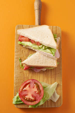 Healthy ham and cheese sandwich with tomato and lettuce in orange backgroundの写真素材