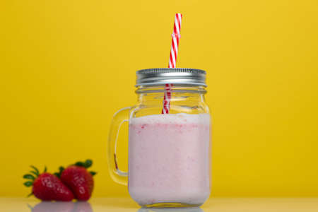 Strawberry smoothie on yellow background with strawberriesの写真素材