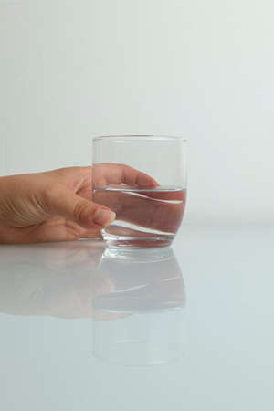 Hand catching glass of water splashing on white backgroundの写真素材