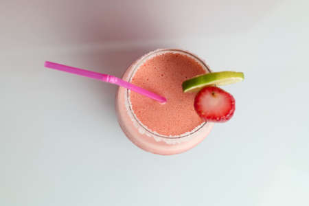 Strawberry cocktail with drinking straw on red backgroundの写真素材
