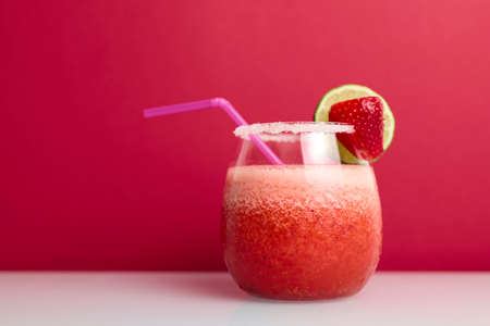 Strawberry cocktail with drinking straw on red backgroundの写真素材
