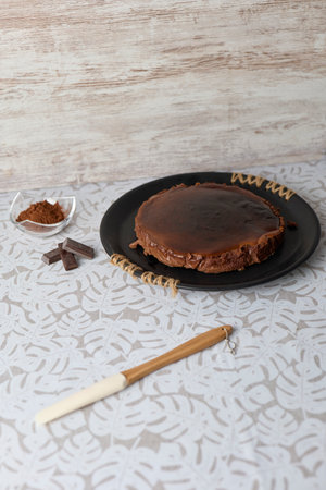Chocolate cake on black plate and wooden spoon with cocoa powder on white backgroundの写真素材