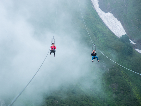 Krasnaya Polyana. Russia. July 28, 2019. Two riders make a downhill cable through the abyss through...
