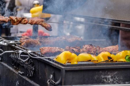 Barbecue on the grill in the aromatic smoke. Appetizing pieces of juicy hot meat on skewers are grilled on charcoal. Traditional Caucasian cuisine on the street.の写真素材