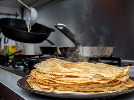 Freshly baked pancakes stacked on a platter from which steam comes. Traditional treat for the...