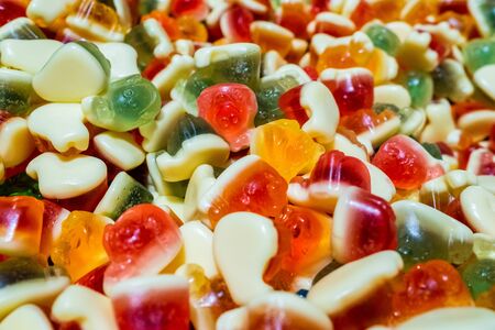 Bright green, yellow, white, orange and red marmalade chewing sweets. Sweet beautiful delicacy made from gel fruit juices. Colorful background. Randomly heaped goodies.の写真素材
