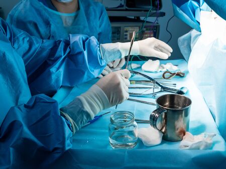 A group of surgeons performing minimally invasive surgery on the patient's anus using surgical instruments. Surgeons have sterile blue surgical clothing.の写真素材