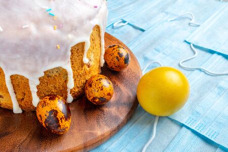 Easter cake and colored chicken and quail eggs are on blue medical masks. Flat lay. Easter holiday...