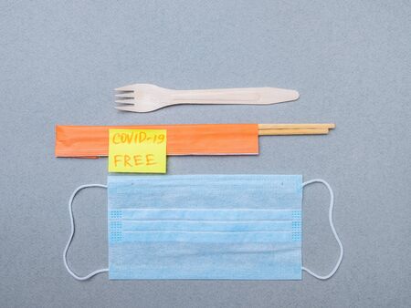 Fork, chopsticks, medical mask and sticker with the inscription covid-19 free on a gray background....