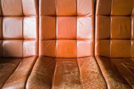 Old vintage brown leather armchairs. Cracked and worn skin from time and frequent use.の写真素材