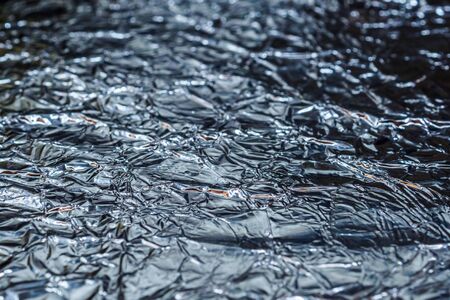 Selective focus on a fragment of the background texture of crumpled aluminum foil. Shiny wrinkled surface.の写真素材