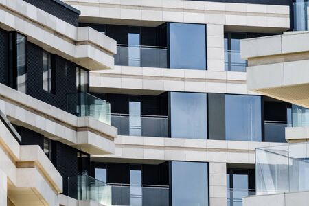 Facade elements of a modern beautiful building in a European city with balconies. Light marble and glass finish with polished chrome steel details. Strict geometric shapes.の写真素材