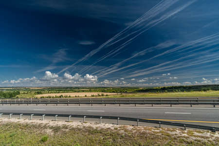 White traces of condensation of water vapor from airplanes over the motorway