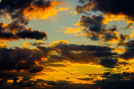 A very dramatic sky full of yellows, blues and oranges. Contrasting clouds during sunset illuminated...