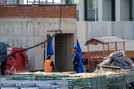 Moscow. Russia. September 06, 2020 Construction workers in uniforms and protective helmets at a construction site among building materials. Summer day. Construction industryのeditorial素材
