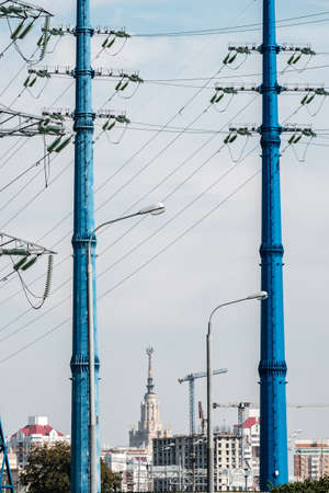 Two blue high voltage power line masts forming a natural framing against the backdrop of urban buildings. Wires and insulatorsの写真素材