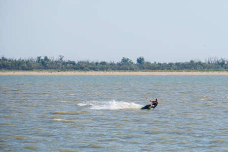 Yasenskaya ferry. Russia. August 18, 2020. Athletic muscular tanned male kitesurfer rushes over the sea waves and jumps, raising splashes of water in bright sunlight on a summer day. Extreme sportsのeditorial素材