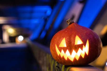 Halloween pumpkin in the dark on a blue industrial abstract background. Blurry colored lights. The decor of the night city in a festive Halloween theme. Copy space.の写真素材