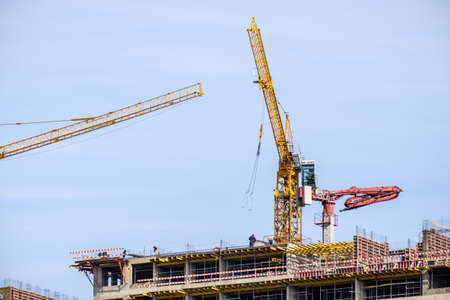 Moscow. Russia. September 06, 2020 View of the construction of a monolithic house against the background of the sky. A tower crane and uniformed workers assembling a reinforcing steel structure.のeditorial素材