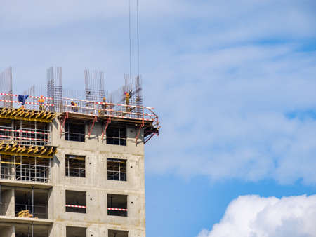 Moscow. Russia. September 06, 2020 View of the construction of a monolithic house against the background of the sky. A tower crane and uniformed workers assembling a reinforcing steel structure.のeditorial素材