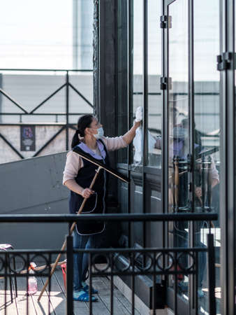 Moscow. Russia. October 4, 2020. A female cleaning service worker washes the large front windows of a buildingのeditorial素材