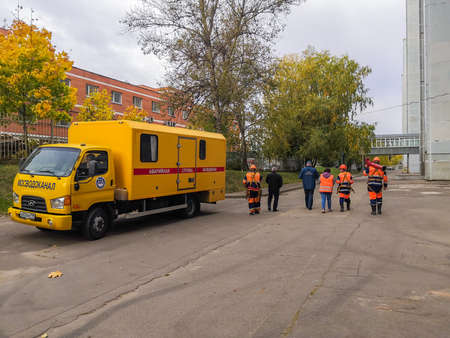 Moscow. Russia. October 7, 2020. Workers in orange uniforms and helmets are walking down the street carrying toolsのeditorial素材