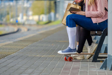 Legs of a girl in white socks and sneakers, leaning on a skateboard.の写真素材