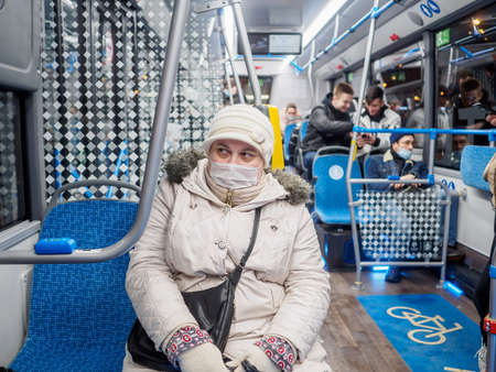 A woman in abus with a medical mask on her face.