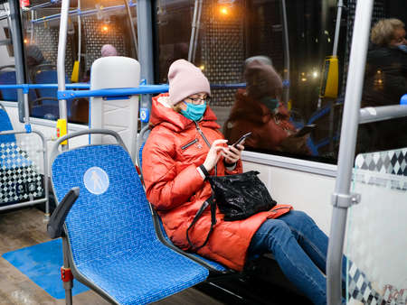 Moscow. Russia. November 23, 2011. A woman in a medical mask with a smartphone in her hands sits...