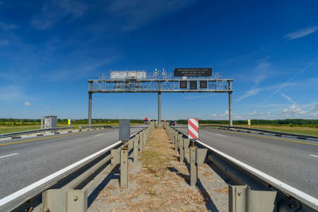 View of the highway on a summer day. Road signs over the road. On the board there is an inscription in Russian: Information about the rules of fare payment. Blue sky. Sunny day.の写真素材