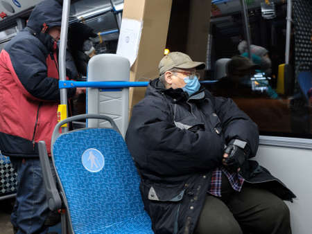 Moscow. Russia. December 2, 2020. A man in a city bus wearing a protective medical mask. Preventive measures for viral infections. The second wave of the coronavirus pandemic.のeditorial素材