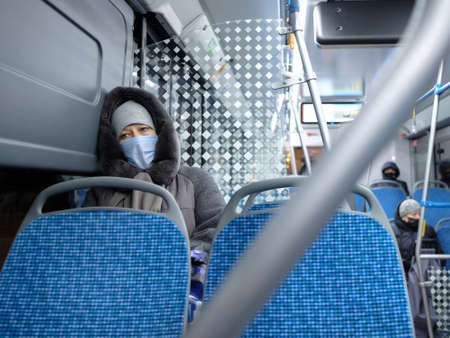 Moscow. Russia. December 2, 2020. Adult woman wearing a surgical protective mask on public transport. Preventive measures to protect against viral infection in public transport.のeditorial素材