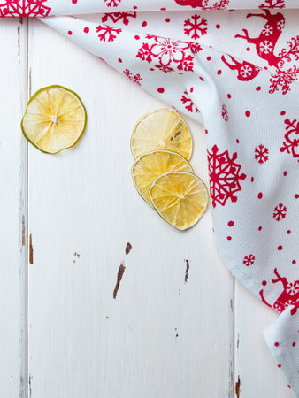 Flat lay. Dried lime slices on white wooden background. Napkin with Christmas ornament. New Year and Christmas decor. Copy space.の写真素材