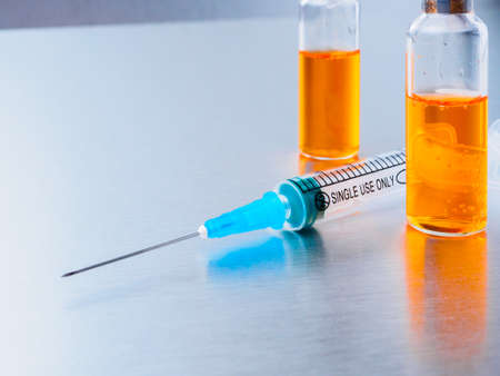 Selective focus. Syringe for injection and two ampoules of  vaccine and on a silvery aluminum...