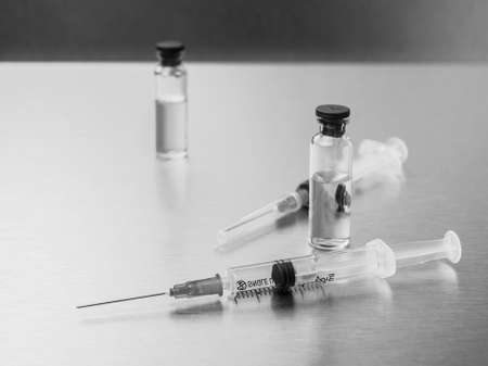 Syringes and ampoules on a polished metal background. Vaccination and immunization concept....
