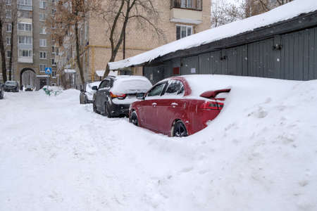 Moscow. Russia. February 13, 2021. Cars parked along the road on a winter day are covered in a thick layer of snow after a heavy snowfall.のeditorial素材