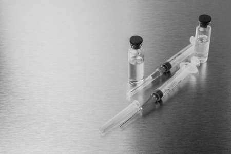 Syringes and ampoules on a polished metal background.の写真素材